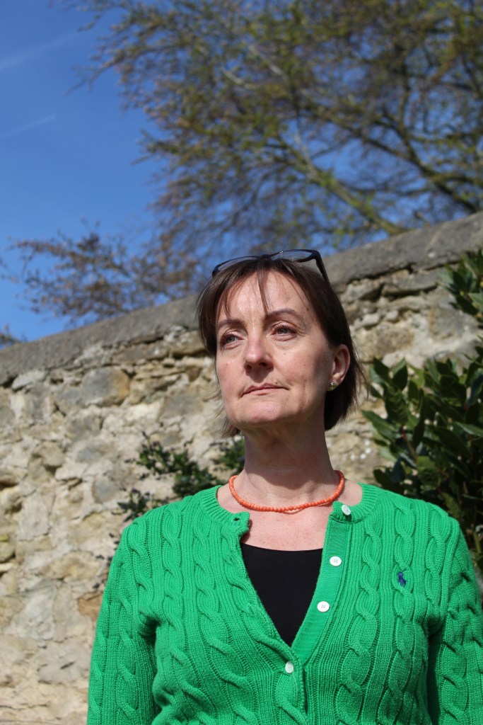 Emma Dandy in garden with cotswold stone wall and bay tree